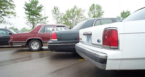 2001 Ford Crown Victoria - Multiple sedans are parked in a lot on a cloudy day.