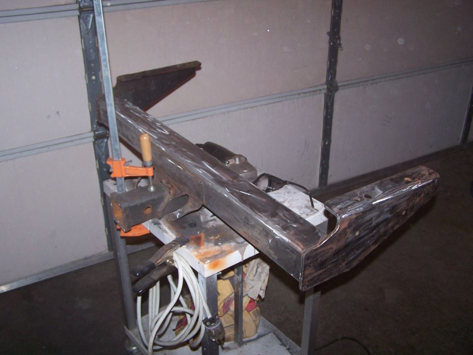 Metal vehicle crossmember clamped on a stand in a garage