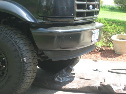 1995 Ford Bronco - Front view of a black Ford Bronco, showing the bumper, tire, and grille detail.
