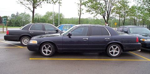 2001 Ford Crown Victoria - A dark blue Ford Crown Victoria is parked in a lot, with another vehicle visible to its left.