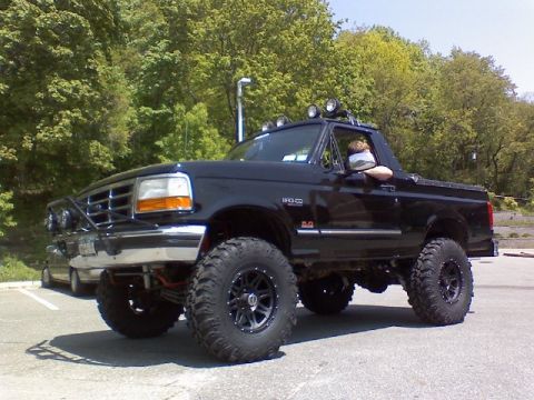 1995 Ford Bronco - A black 1995 Ford Bronco is parked outdoors, modified for off-road use with large tires and a lifted suspension.