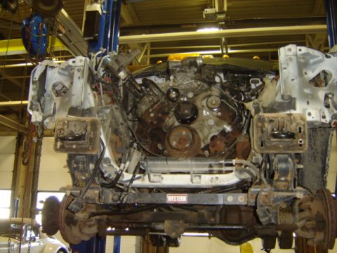 1992 Ford Bronco - The engine and chassis of a vehicle are visible while it is elevated on a lift for maintenance or repair.