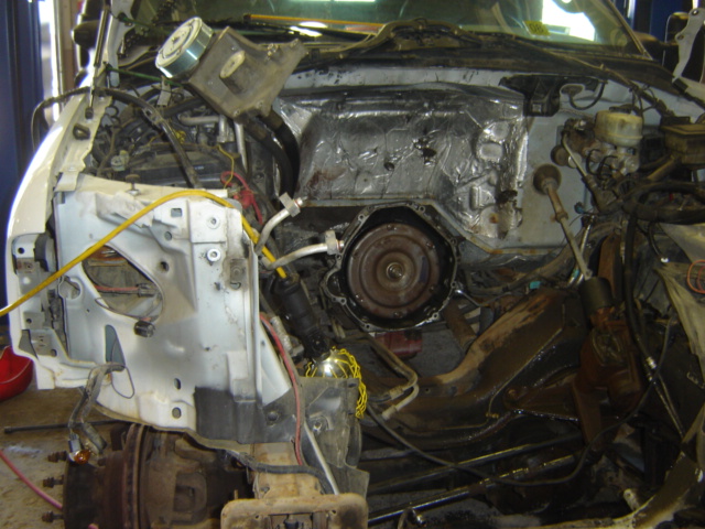 Vehicle engine bay disassembled, showing transmission and engine components. Some insulation is visible