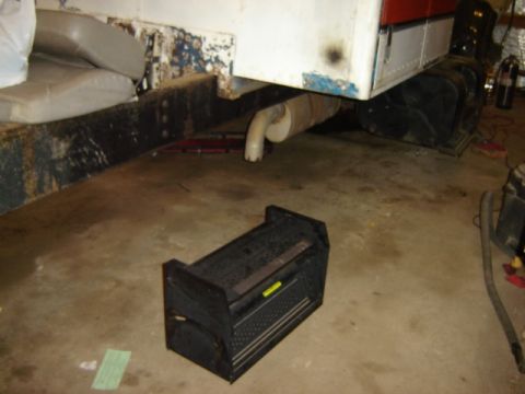 1992 Ford Bronco - A toolbox sits on the floor near the exhaust system of a vehicle in a garage.