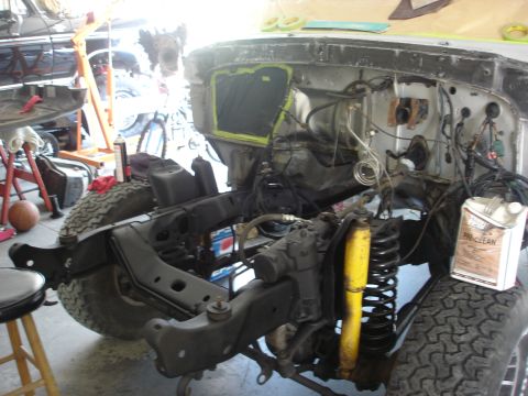1979 Ford Bronco - The front end of a vehicle is disassembled, showing the chassis, engine bay, and suspension components during a repair process.