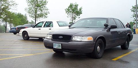 2001 Ford Crown Victoria - Two Ford Crown Victoria police cars parked in a lot on a cloudy day.