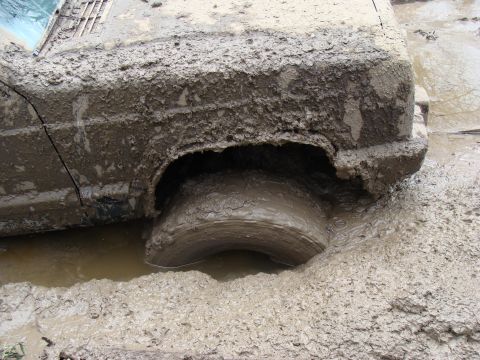 1992 Ford Bronco - This vehicle is deeply mired in thick mud, with its wheel submerged.