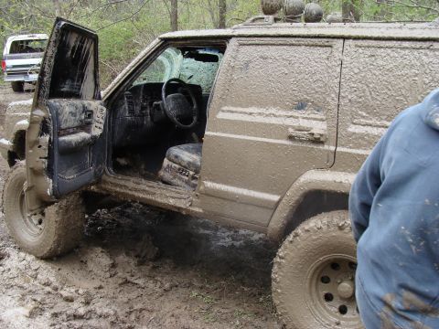 1992 Ford Bronco - This Jeep Cherokee is covered in mud after an off-road adventure, with another vehicle visible behind it.