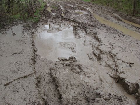 1992 Ford Bronco - Off-road track covered in thick mud and puddles, showing deep tire imprints.