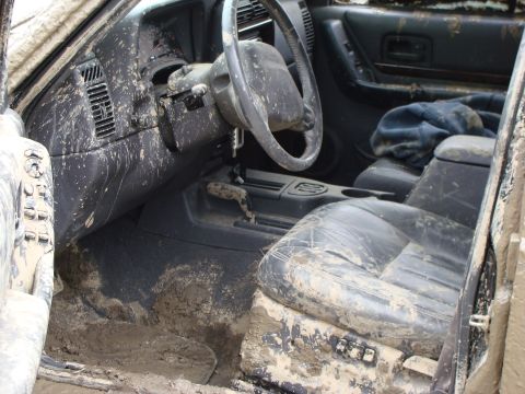 1992 Ford Bronco - The interior of a vehicle is heavily covered in mud, obscuring most details.