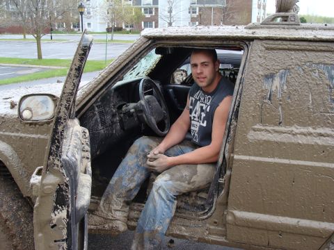 1992 Ford Bronco - A man sits in the mud-splattered interior of an SUV after an off-road excursion.