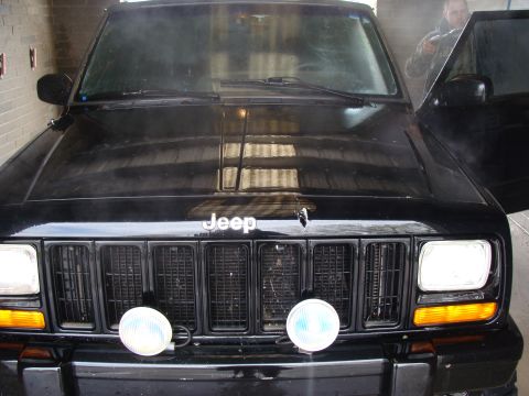 1992 Ford Bronco - A black Jeep Cherokee XJ is shown from the front with its driver's door open and a person visible inside.