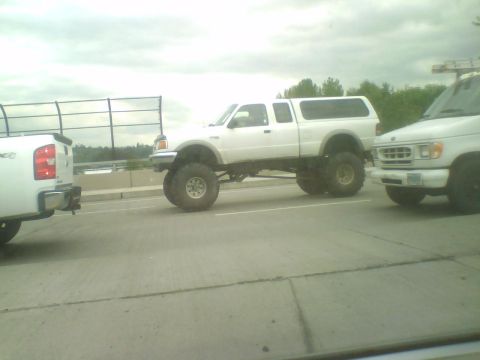 1993 Ford Bronco - A lifted white Ford Ranger pickup truck with a camper shell is seen on the highway.