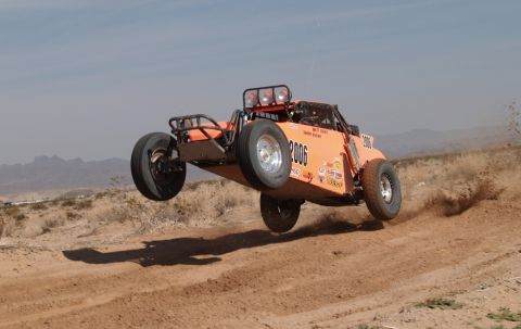 2008 Ford Bronco - An orange off-road buggy soars through the air over a dirt track in a desert landscape.