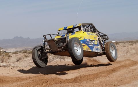 2008 Ford Bronco - A custom-built off-road buggy is captured airborne during a race in a desert landscape.
