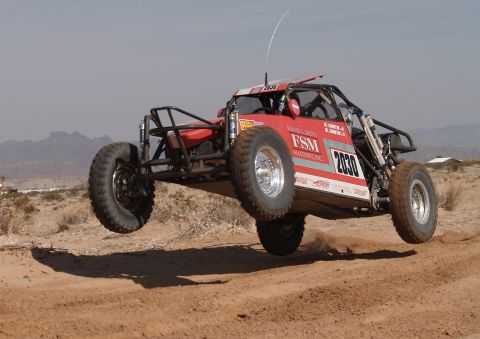 2008 Ford Bronco - Off-road buggy jumps during a race in a desert environment.