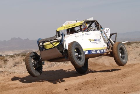 2008 Ford Bronco - This off-road buggy is mid-air during a race, kicking up dust on a desert track.