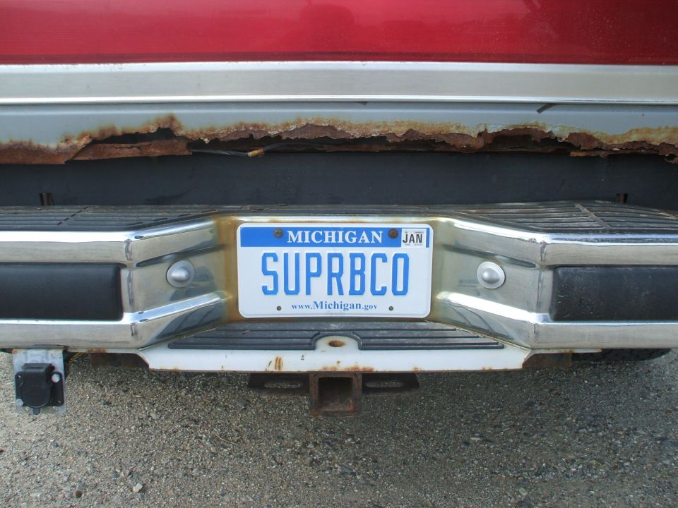 Rear bumper with Michigan license plate reading SUPRBC0, showing rust on the body panel above