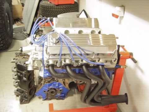 1996 Ford Bronco - A V8 engine is mounted on an orange engine stand, ready for installation or work.