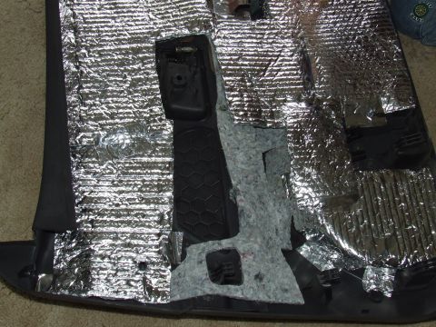 2003 Ford Crown Victoria - Close-up of a car's interior door panel, showing sound deadening material applied over black plastic components.