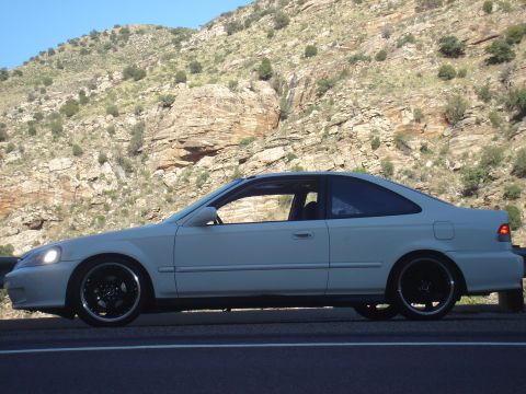 1997 Ford Probe - Side view of a white coupe parked on the side of a road with a mountain backdrop.