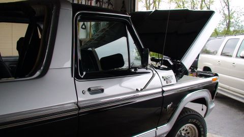 1979 Ford Bronco - A two-tone black and silver 1978 Ford Bronco is parked in a garage with its hood open, alongside a white SUV.