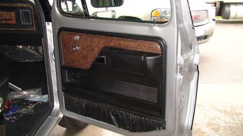 1979 Ford Bronco - Interior view of a 1979 Ford Bronco, focusing on the door panel with wood grain accents and black trim.