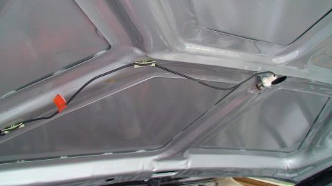 1979 Ford Bronco - The underside of a car hood shows wiring and clips, with a small orange marker.