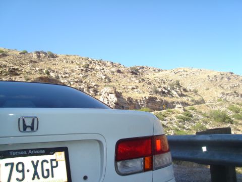1997 Ford Probe - Rear view of a white Honda sedan parked on a scenic mountain road with a clear blue sky.