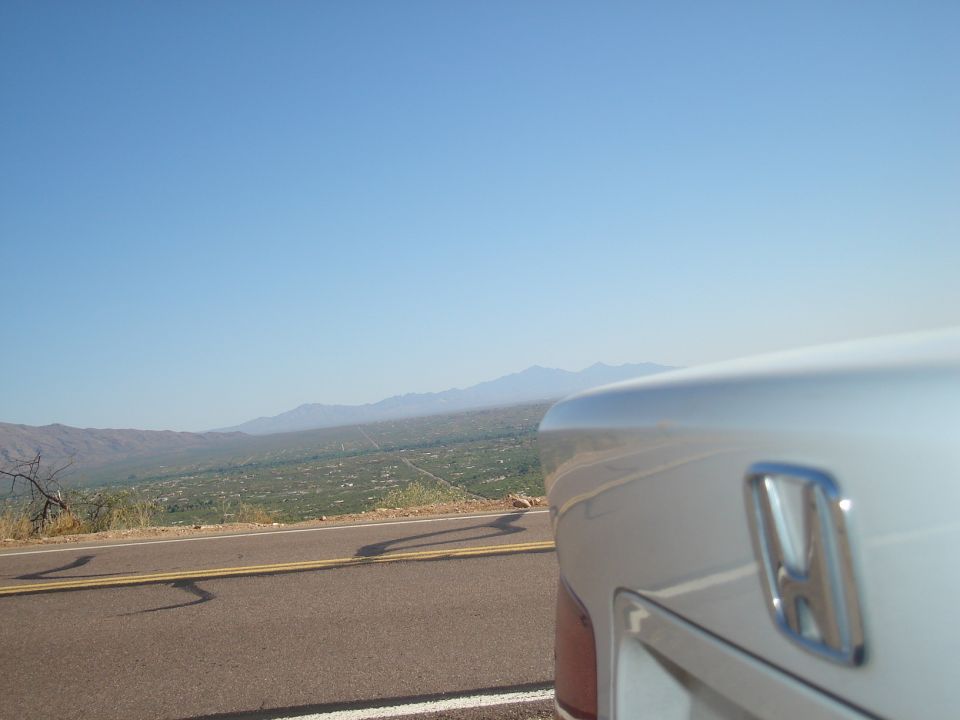 Silver car rear quarter panel with Honda emblem, overlooking a valley