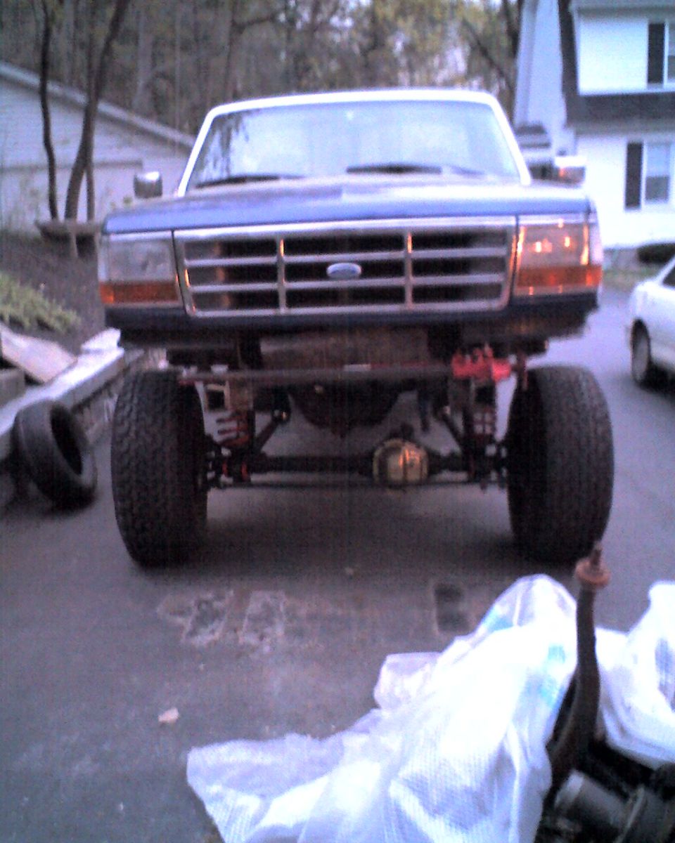 Front view of a blue 1996 Ford F-150 truck with lifted suspension