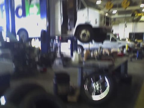 1992 Ford Bronco - A truck is suspended on a lift in a garage, with another vehicle bearing a FedEx logo visible in the background.