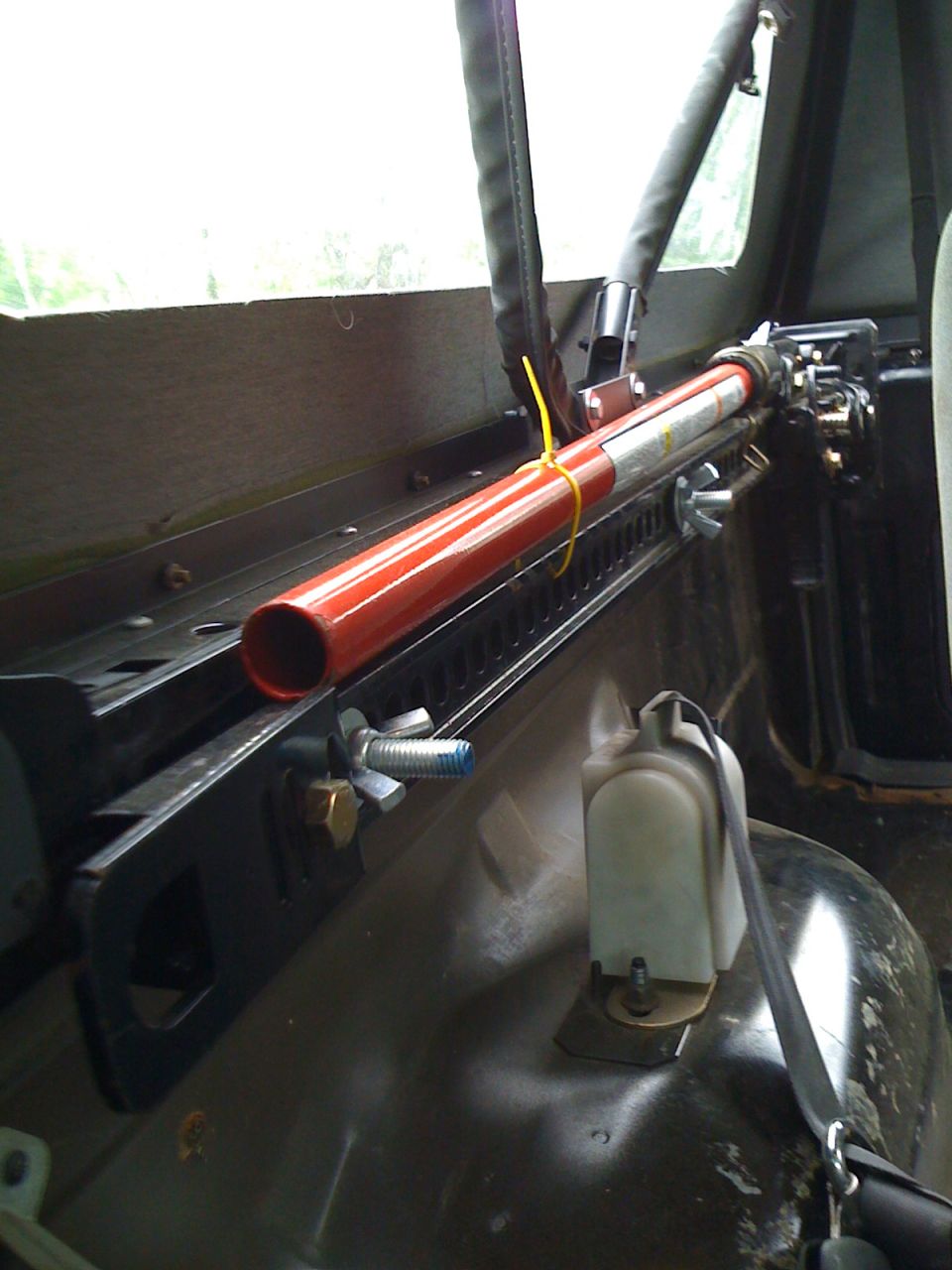 Red Hi-Lift jack mounted on black brackets inside a vehicle's cargo area