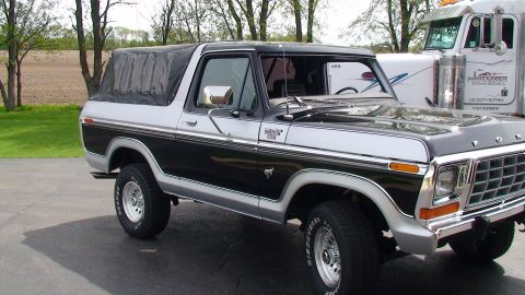 1979 Ford Bronco - This two-tone Ford Bronco is shown from the front three-quarter view, with a large truck in the background.