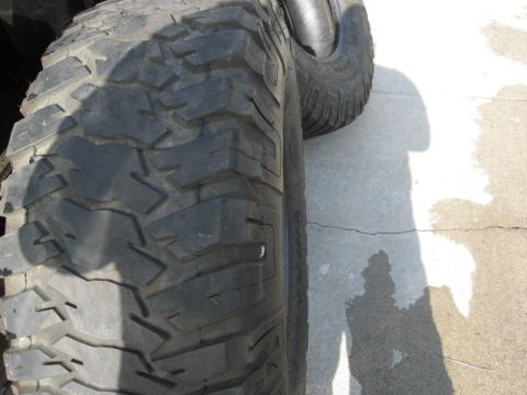 1986 Ford Bronco - A close-up view of a tire tread pattern is visible, with a shadow on the ground.