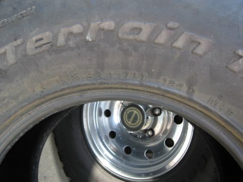 1986 Ford Bronco - A close-up view of a BFGoodrich All-Terrain tire and a chrome wheel with a center cap.
