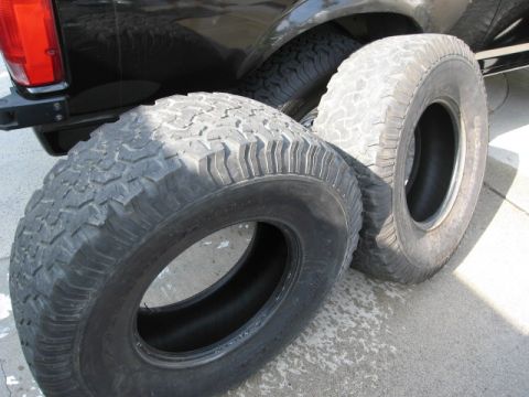 1986 Ford Bronco - Several large off-road tires are displayed, with one still attached to a black vehicle.