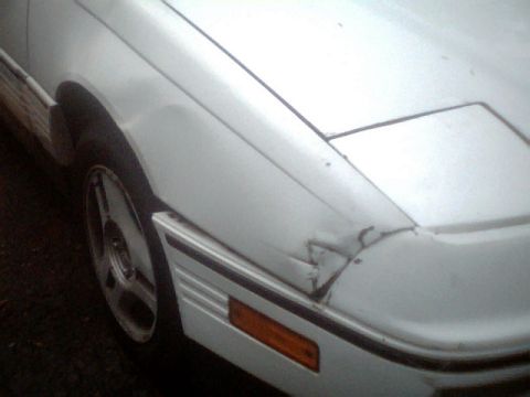 1989 Ford Probe - Front corner of a white car shows damage to the fender and bumper area.