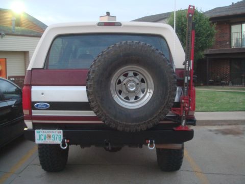 1992 Ford Bronco - Rear view of a two-tone burgundy and cream full-size Ford SUV wearing an Oklahoma plate (JCV 978), fitted with a custom black steel rear bu…