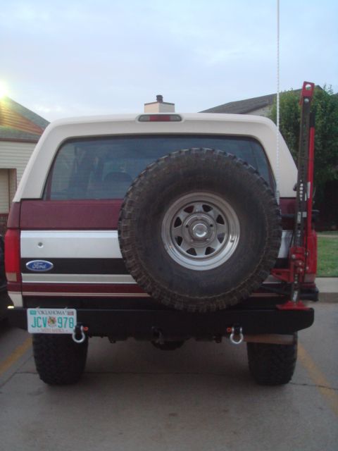 1992 Ford Bronco - Tall portrait rear view of a burgundy and cream Ford Bronco with an Oklahoma plate reading JCV 978, showing a fabricated black steel rear b…