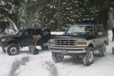 1993 Ford Bronco - A two-tone 1993 Ford Bronco is parked in the snow next to a black Toyota Tacoma pickup truck.