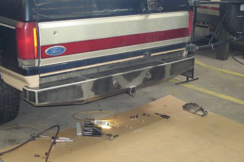 1993 Ford Bronco - The rear of a Ford truck shows a custom metal bumper with a trailer hitch receiver, with tools nearby.