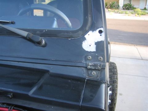 1987 Suzuki Samurai - This Suzuki Samurai shows evidence of body repair on the door frame, with visible filler material and screw heads.