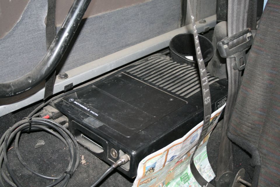 Motorola radio unit with cables and a folded map on the floor of a vehicle