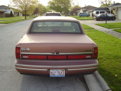 1996 Ford F-150 - The rear of a tan 1996 Lincoln Town Car is shown parked on a suburban street.