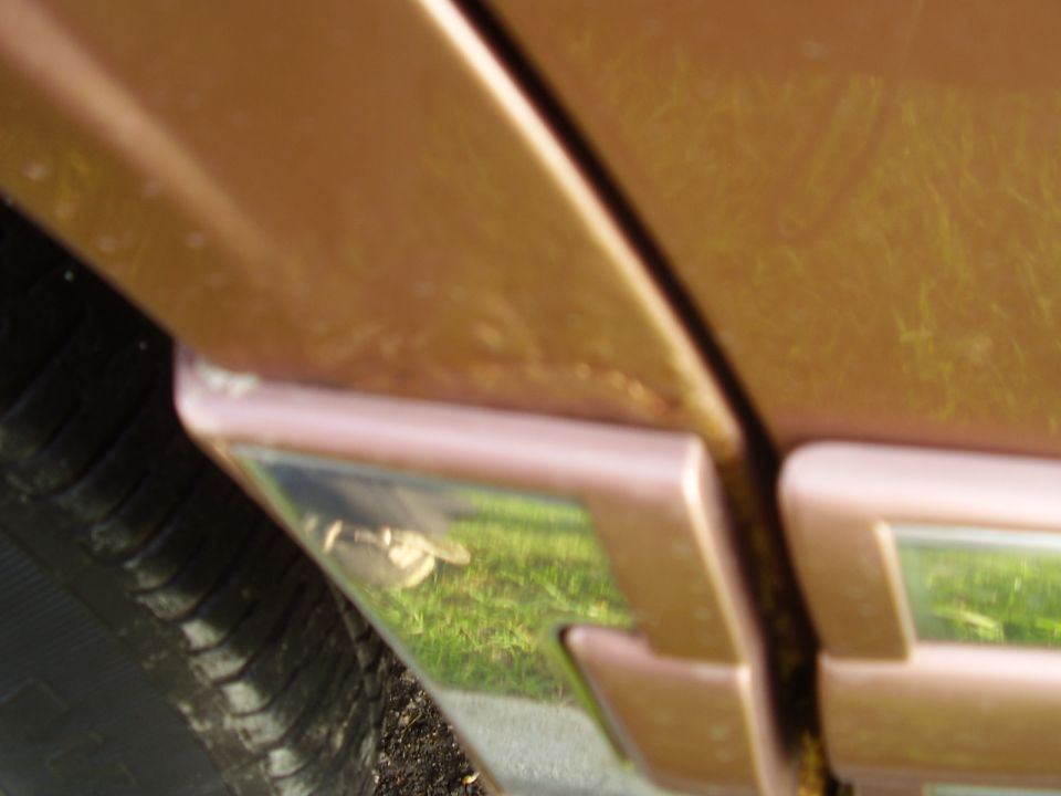 Close-up of a copper-colored truck's door seam and a portion of the tire