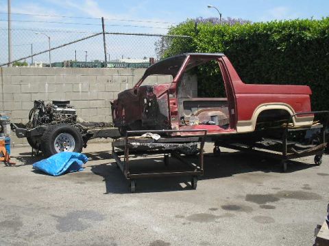 1986 Ford Bronco - A disassembled 1980s Ford Bronco is shown in a yard with its body and chassis separated.