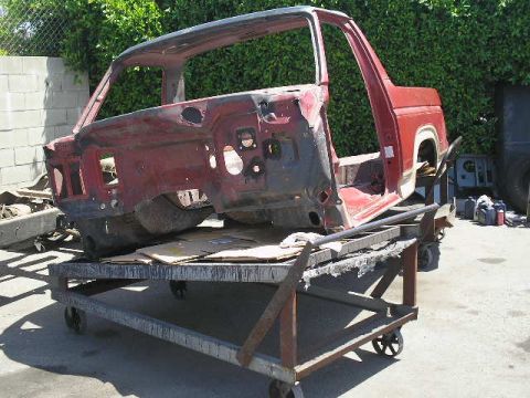 1986 Ford Bronco - The body of a red 1986 Ford Bronco sits on a rolling cart, stripped down for a tear-down.