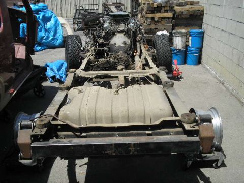 1986 Ford Bronco - The chassis of a disassembled vehicle is shown from the rear, with the engine and fuel tank visible.
