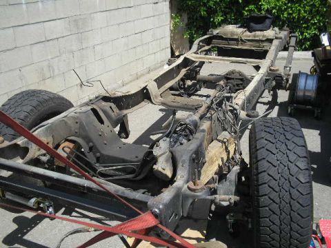 1986 Ford Bronco - The bare frame and chassis of a vehicle are shown, with suspension components and tires attached.